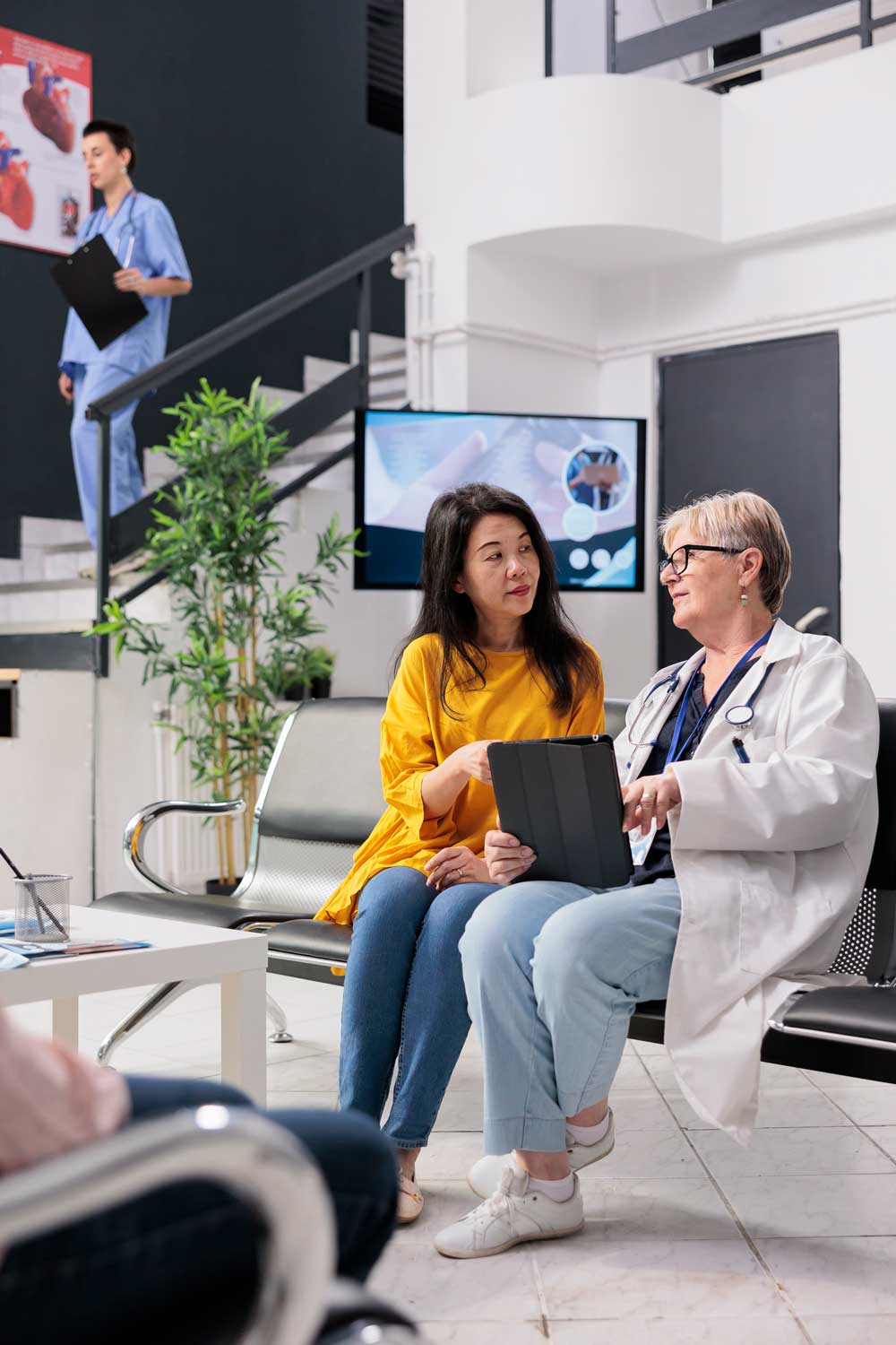 A female doctor and female patient confer while sitting in the lobby of a clinic